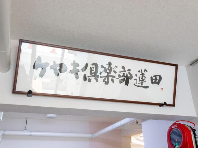書かれた掲示物が映る空間 掲示物 掲示された言葉が、日々の心構えやモットーを感じさせる空間です。壁にAEDの設置も見受けられます。