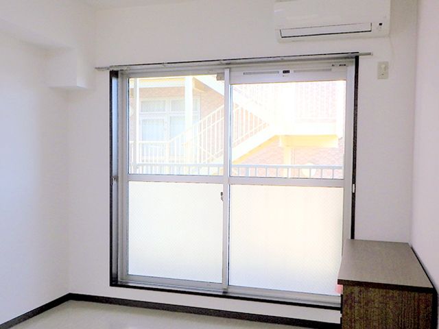 明るい洋室の窓とエアコン 居室 広々とした清潔感あふれる居室です。窓からの自然な光が心地よい癒しの空間を提供しています。