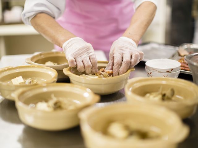 調理中の手仕事 食事 手袋をした手で丁寧に食事の準備をしている様子です。利用者の方への気配りが感じられる温かい雰囲気が伝わってきます。