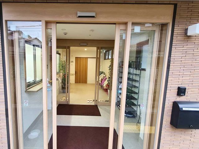 明るいエントランスの風景 玄関 手入れが行き届いたエントランスは訪問者を優しく迎え、安心感を与えます。ゆったりとした開放感のある受付空間が、快適な職場環境を予感させます。