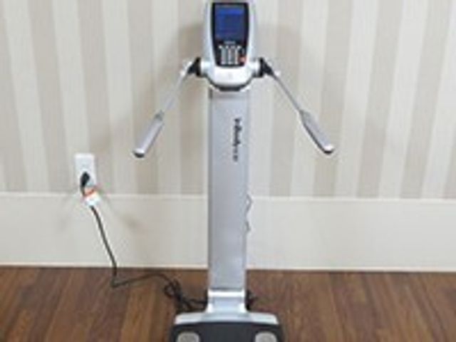 運動支援機器と壁紙 インボディ〈体成分分析装置〉 最新の運動支援機器が備わった機能訓練室で、ご利用者の健康をサポートします。優しい色合いの壁は落ち着いた雰囲気を演出しています。