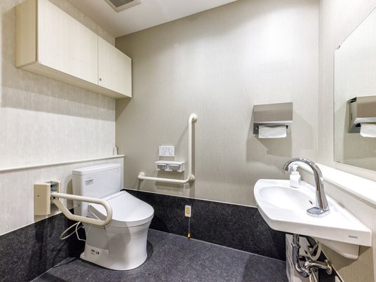 広い空間でL字の手すりがついている洋式トイレ