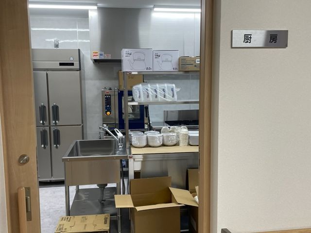 整備された清潔なキッチン 厨房 清掃が行き届いており、食器も整然と並べられた環境です。日々の食事の準備をする場所として、清潔感が感じられます。