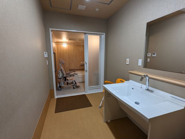 浴室付き洗面台の空間 脱衣所 やわらかな光で照らされた清潔感のある浴室です。車椅子対応の広々とした設計で、快適にご利用いただけます。