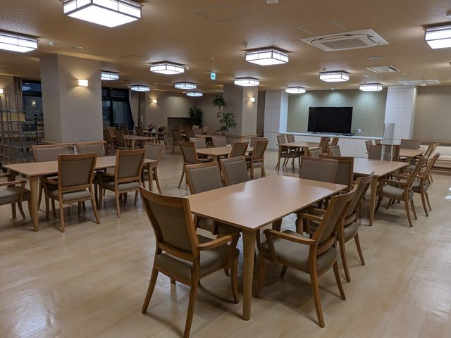広々とした共有ダイニング 共有スペース ゆとりのある食堂は、集いの場として利用可能です。座席や大型テレビが備えられた明るい空間をご覧ください。