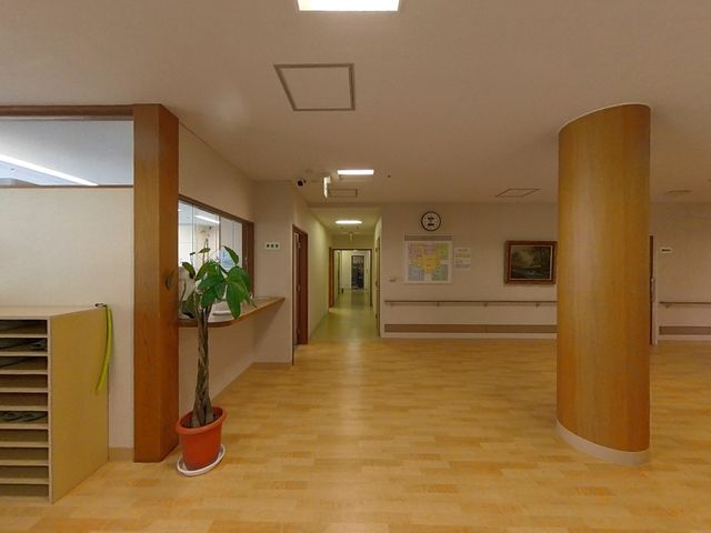 明るい廊下の風景 窓口 木目調のアクセントが心地よい休憩スペースです。清潔感溢れる廊下は、日常の移動も快適に感じられる設計になっています。