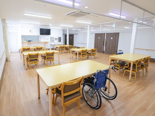 広々とした明るい食堂 ダイニングルーム 木製のテーブルと椅子が並ぶ清潔なダイニングスペースです。車椅子にも対応し、安心して食事の時間を過ごせる環境が整っています。