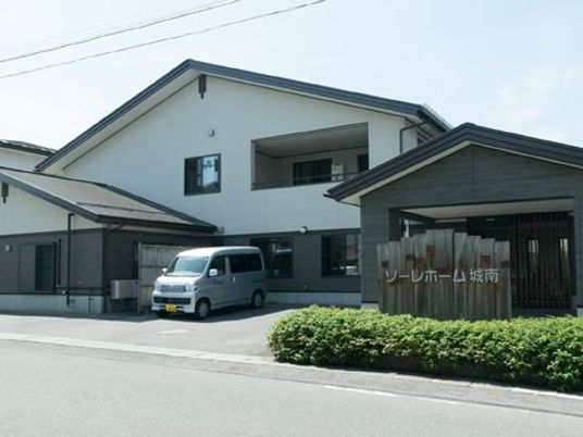 白い建物と送迎車の外観