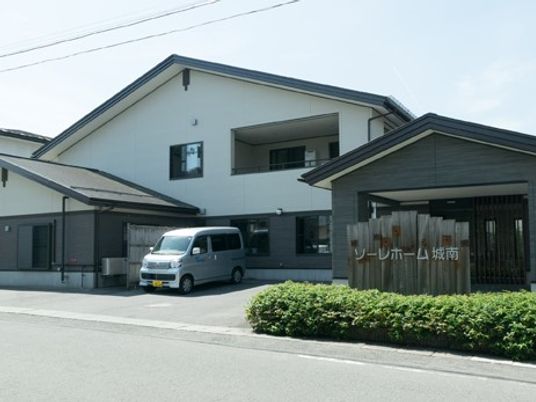 白い建物と送迎車の外観
