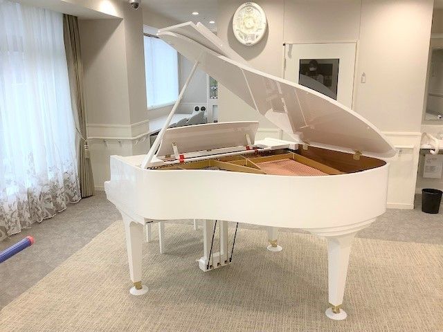 白色グランドピアノのある部屋 食堂 清潔感溢れる多目的室には、音楽を楽しめる白いグランドピアノが置かれ、ゆったりとした時間を提供しています。