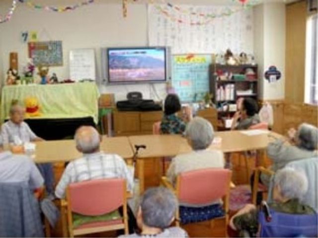 テレビを見る利用者 談話室 居心地の良い共有スペースで、利用者同士がテレビ視聴を楽しんでいる様子です。ゆったりとした雰囲気の中で、交流を深めることができます。