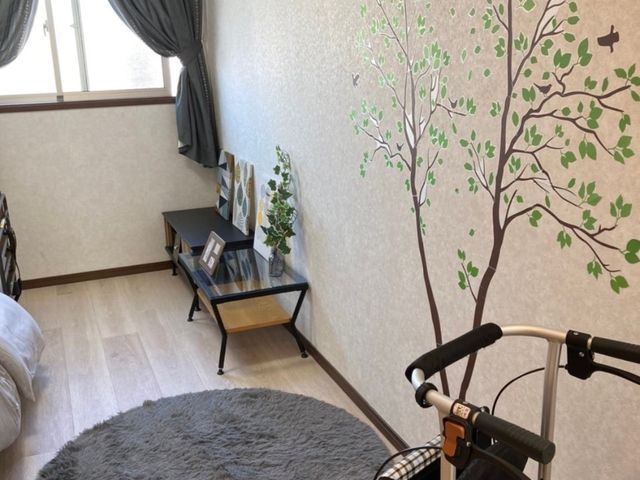 居心地の良い居室空間 居室 ぬくもりを感じさせるデザインの壁が特徴的な居室です。移動をサポートする歩行器が、ゆとりある生活を支えています。