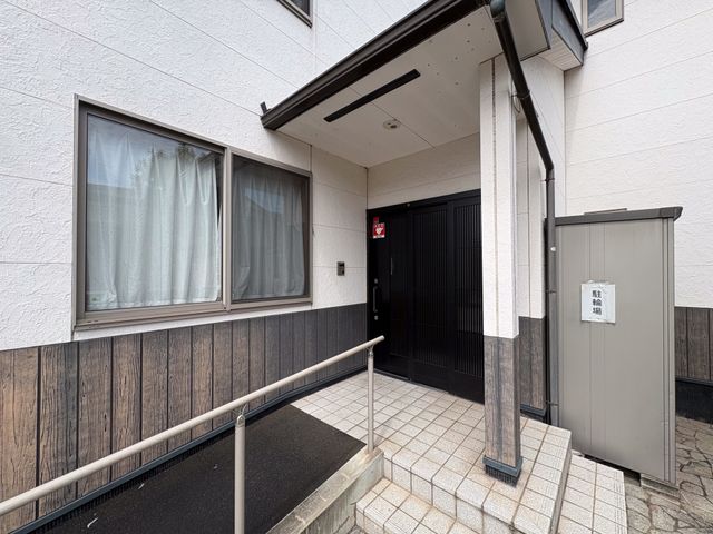 段差の少ない玄関先 エントランス   手すり付きのスロープがあり、出入りしやすい玄関まわりです。落ち着いた外観で、来訪者を迎える印象があります。