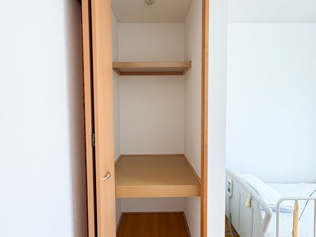 収納付き居室の一角 居室   木目の収納が備わった居室の一角です。ベッド横にゆとりがあり、落ち着いて使いやすい印象です。