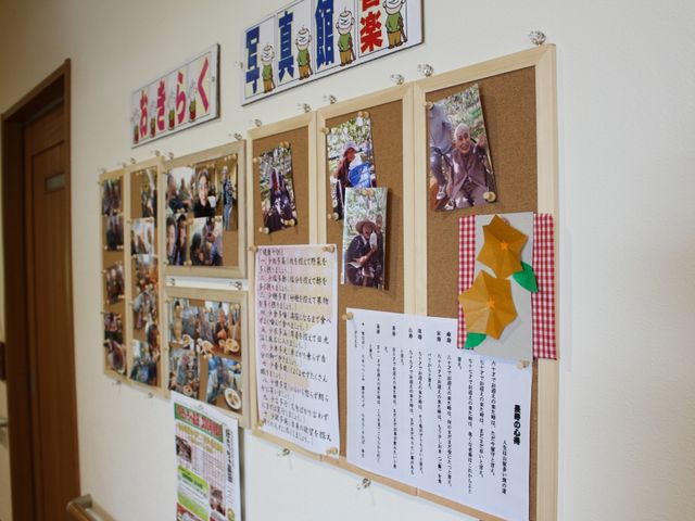 廊下の掲示ボード 施設内の写真館 手作りの工作品や笑顔あふれるイベント写真が飾られた掲示ボード。毎日の生活が楽しさに満ちている様子が伝わります。