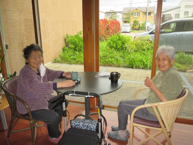 笑顔で会話する入居者様 ラウンジ 窓辺で向かい合って笑顔でお話されている様子が印象的です。心地よい休息のひとときをお過ごしいただけます。