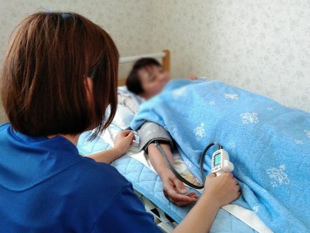 居室にてバイタル確認 居室 居室では、健康状態の確認が行われています。温かみのある空間で安心して過ごせます。