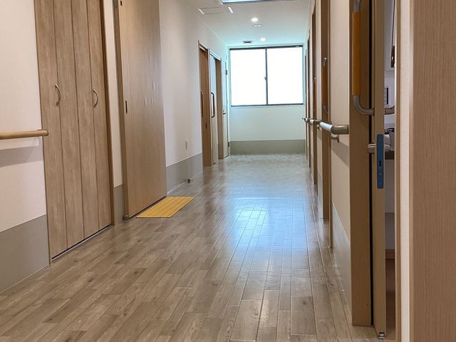 整った施設の廊下の光景 廊下 床材に木目調を採用し、温かみのあるデザインの廊下です。訪れる方々を優しく迎え入れます。