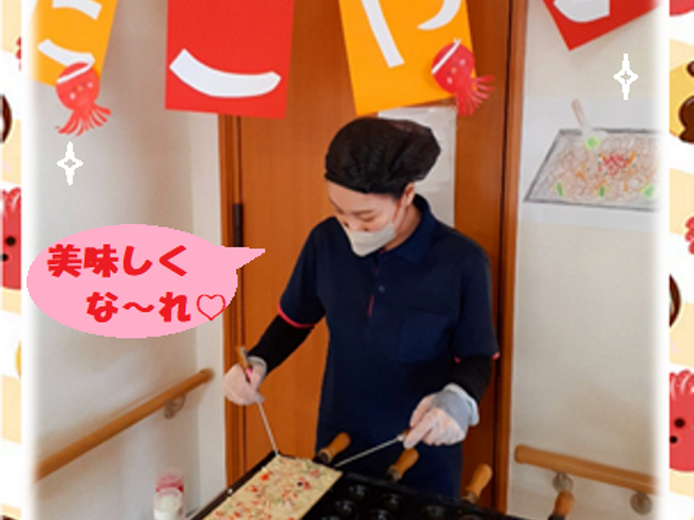 たこ焼きイベントの様子 多目的室 笑顔でたこ焼きを焼くスタッフの手元。手作りの飾り付けが心温まるイベントの一コマです。