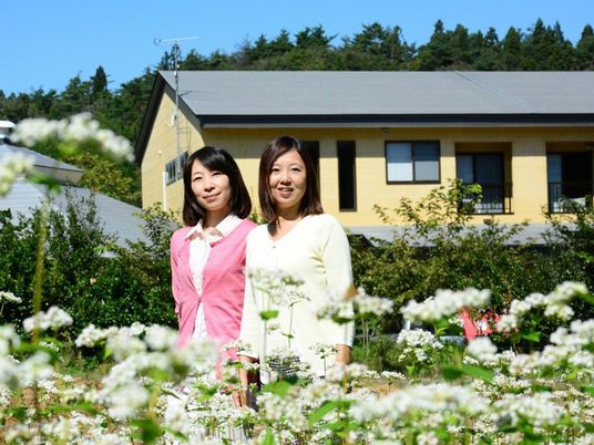 花壇の前の女性と建物外観  