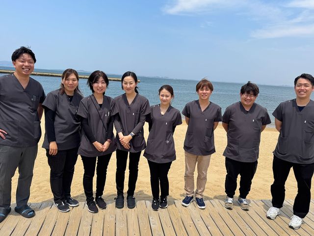 スタッフの笑顔 スタッフイメージ 海を背景にした明るい雰囲気の中で、スタッフが協力して働くことをイメージできます。