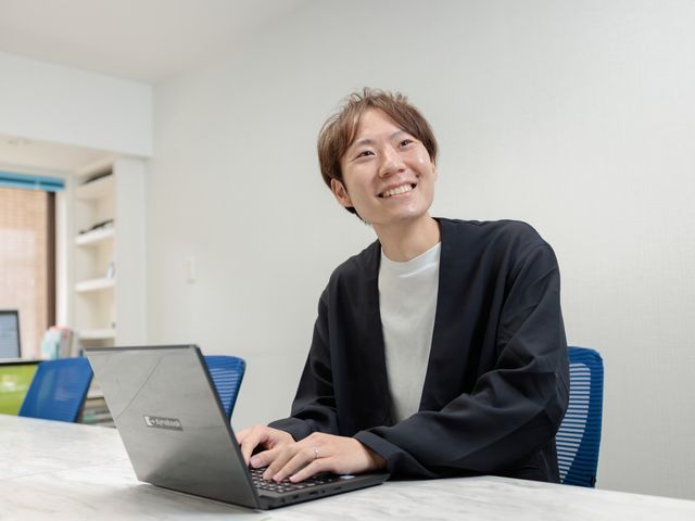 職員の様子と笑顔 スタッフイメージ 笑顔でパソコン作業中の様子です。働く環境の雰囲気を感じ取れます。