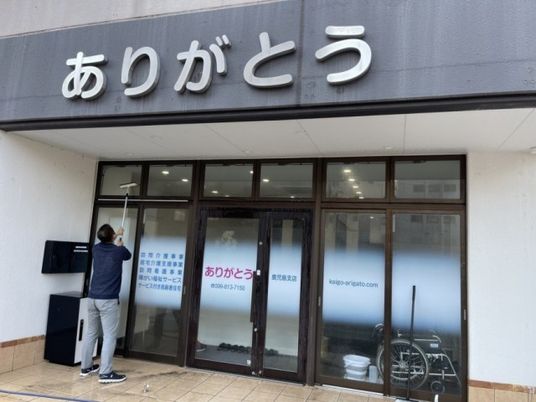 外観で窓拭きする人  