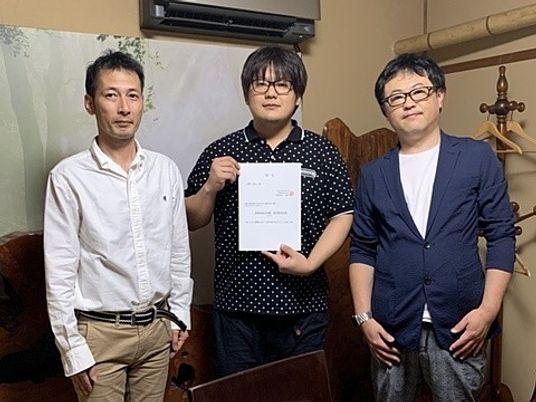 3人が並ぶ室内  