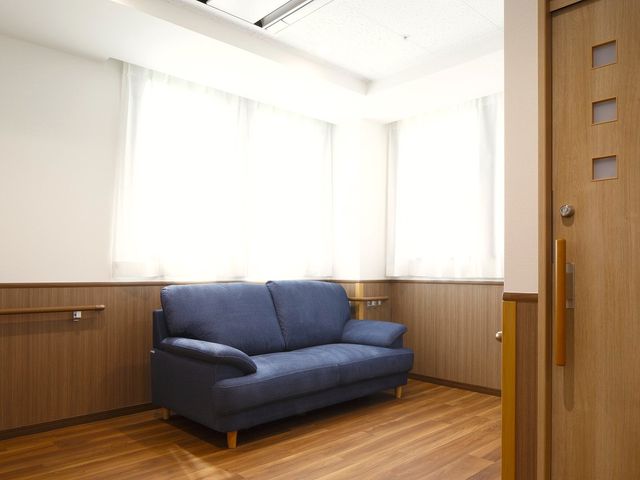 落ち着いた色合いの居室 居室 ゆったりとした青いソファが特徴の居室です。柔らかな光が差し込み、穏やかな時間をお過ごしいただけます。