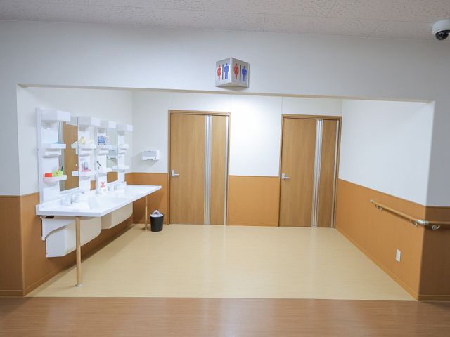 明るい洗面台エリア 洗面台 手すりが設置され、車椅子でも利用しやすい洗面エリアです。清潔感のある空間が保たれています。