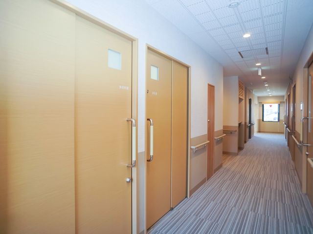 明るい廊下の居室扉 廊下 手すりが設置された清潔で広々とした廊下は、快適な移動空間を提供しています。