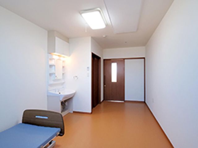 居室のベッドと洗面台 居室１ 清潔感溢れる居室で、ゆったりと過ごせる広さと機能性が整っています。ベッド周りもすっきりしており、日々の快適さが保たれる設計です。