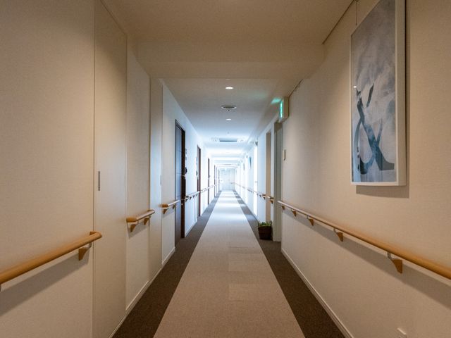 清潔感のある廊下 廊下 手すりが取り付けられた広々とした廊下。壁には絵が飾られ、温かみのある雰囲気を提供しています。