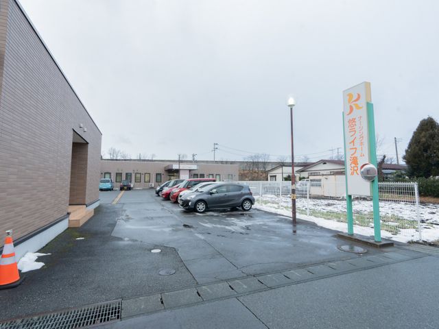駐車場と看板の外観 外観 広々とした駐車スペースがあり、通勤が便利です。施設の看板が目印になっています。