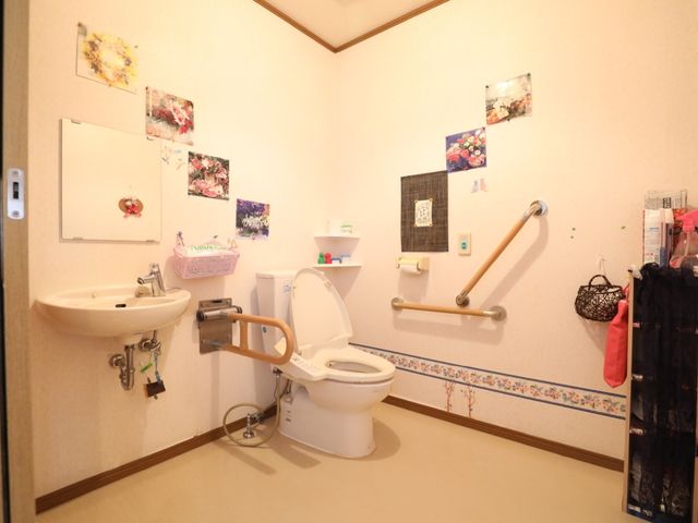手すり付きトイレ空間 トイレ 手すりが整った安心のトイレ空間です。壁にはカラフルな飾りがあり、温かみのある雰囲気が漂います。