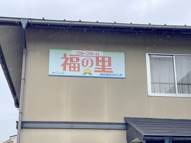 温もり溢れる施設の看板 看板 ご高齢の方々へ向けた、ぬくもりある明るい看板が目を引きます。周囲の落ち着いた配色が和やかな雰囲気を演出しています。