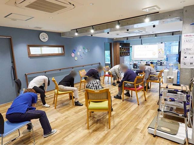 体操する方々の機能訓練室 機能訓練室 広々とした明るい空間で、専門スタッフの指導のもと体操が行われています。自然光が差し込むので、気持ちよく過ごせます。