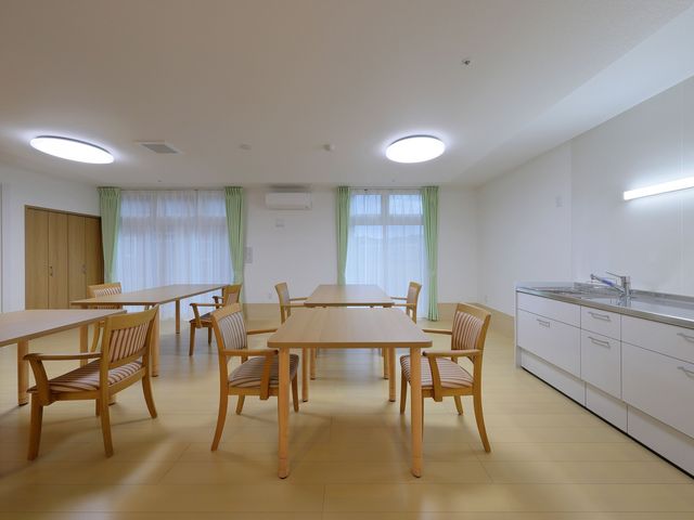 職員と利用者の食事風景 食堂 中庭で利用者様と共に穏やかな食事の時間を支える、やりがいのある職場です。