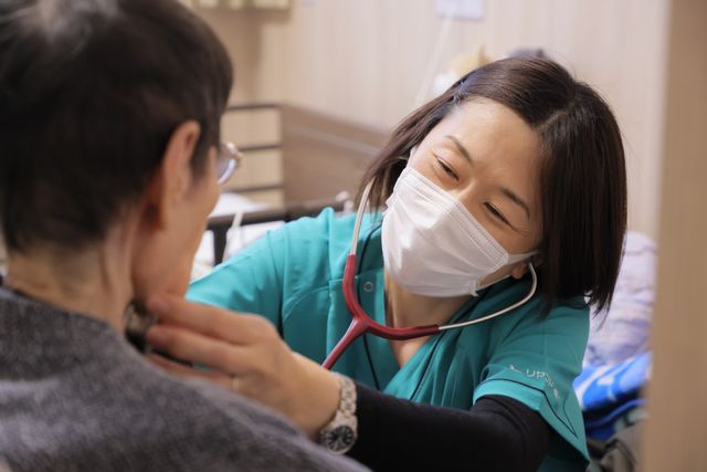 笑顔の介護士が対応する場面 スタッフイメージ 優しい表情のスタッフが入居者と向き合い、安心感のあるコミュニケーションを図っています。
