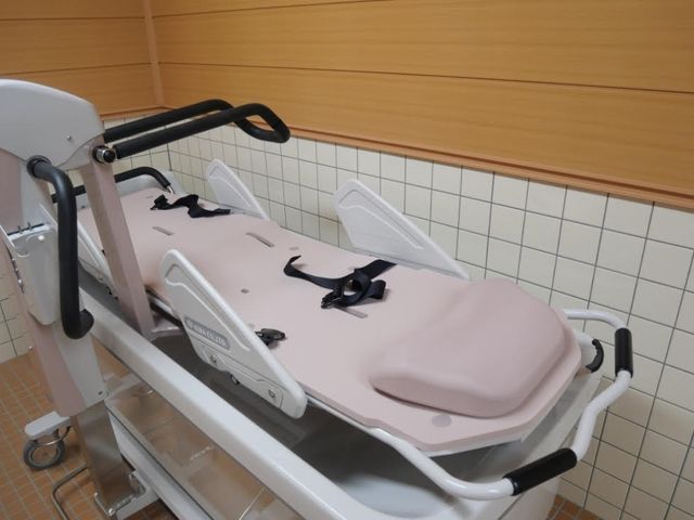 幸せな様子の高齢者中庭 機械浴室 笑顔溢れるご高齢の方々に囲まれ、やりがいのある職場で大切な時間を過ごしましょう。