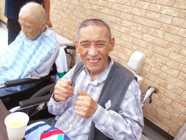 笑顔のご高齢者と車椅子 サポート 庭で過ごすご入居者が笑顔で快適なひとときを楽しんでいる様子。ここでは日々、心温まる交流が生まれています。