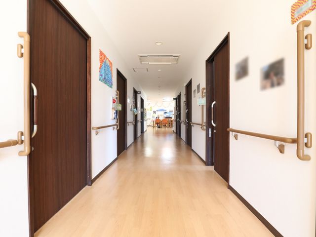 明るい廊下 通路 手すりが整った広々とした廊下です。壁にはアートが飾られ、温かみのある雰囲気を演出しています。