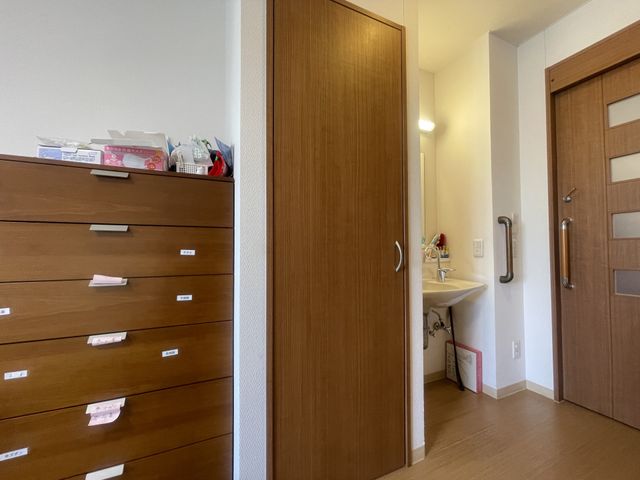 木製家具と洗面台の居室 居室 収納力のある木製家具と清潔感のある洗面台が配置されています。落ち着いた環境での生活が可能です。