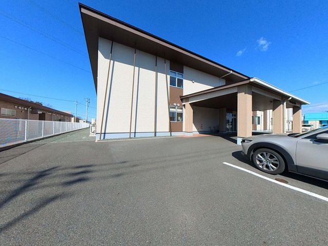 明るい外観の建物 外観 広々とした駐車スペースを備えた施設です。青空の下で、快適な環境を感じられます。
