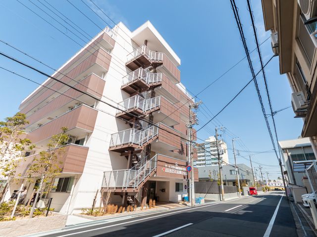住宅街の建物外観 外観 多層構造で整然とした施設は、青空の下でゆったりとした雰囲気を感じさせます。