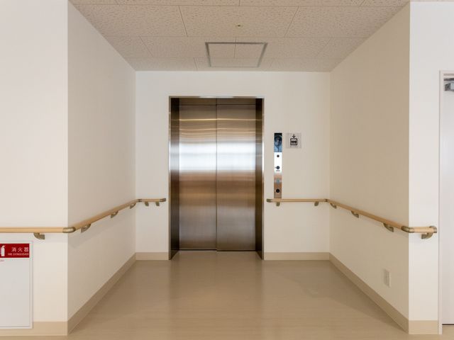 手すり付きのエレベーター前 エレベーター 手すりが設けられたエレベーター前、移動の安全をサポートします。安心してお過ごしいただける環境です。