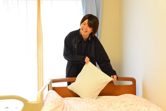 笑顔でベッドメイクするスタッフ