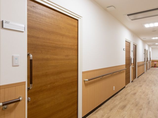 落ち着いた廊下 廊下 木目調のデザインが施された落ち着いた印象の廊下です。両側にはしっかりとした手すりが設置されていますので、安全に移動することができます。