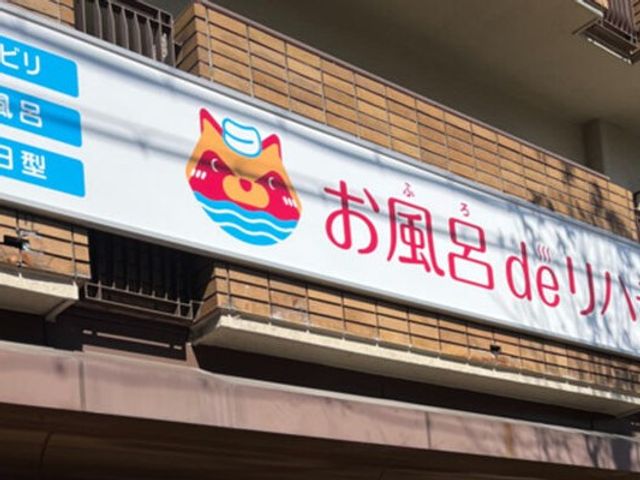 お風呂の看板外観 外観   建物の外側に、カラフルな浴槽のマーク付き看板が掲げられています。施設の案内が見つけやすい出入口まわりです。