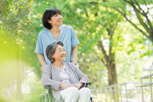 笑顔の介護士と利用者が庭を楽しむ様子